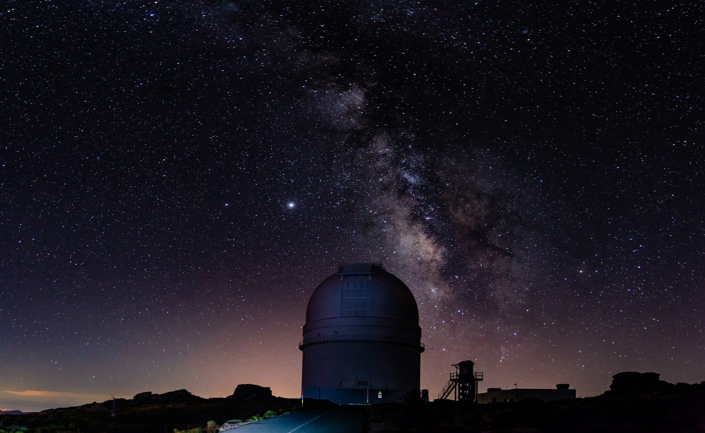 Telescope beneath a star-filled sky with meteors